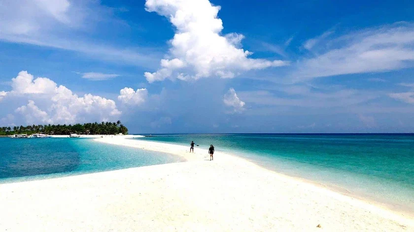 Aerial view of Bounty Beach on Malapascua Island at sunset with bangkas anchored offshore and the small island's interior visible in the background